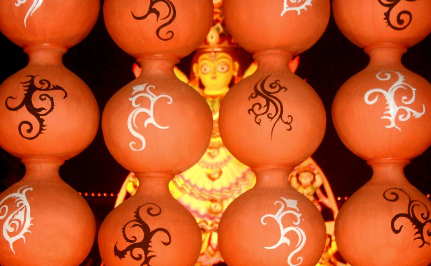 A glimpse of a tribal themed idol through a pandal made of traditional water pitchers, 2017.